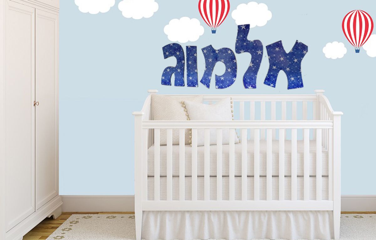 מדבקת קיר עם שם אלמוג וכיתוב כוכבים מעל מיטת תינוק בחדר ילדים מעוצב